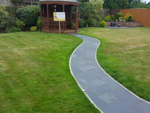 A curved stone path through a lush green lawn leading to a gazebo.